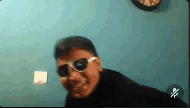 a boy wearing sunglasses is smiling in front of a clock on the wall .
