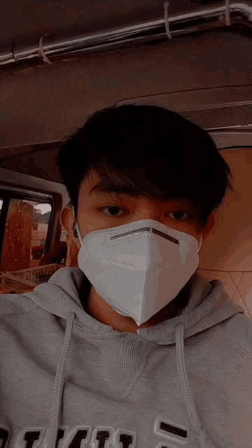 a young man wearing a mask and a grey hoodie