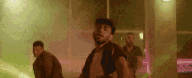 a man with a beard is dancing in a room with other people