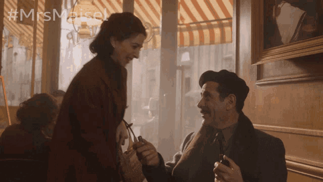 a man and a woman are looking at each other with #mrs maisel written on the bottom