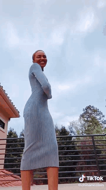 a woman in a blue dress is standing on a balcony with a tik tok watermark
