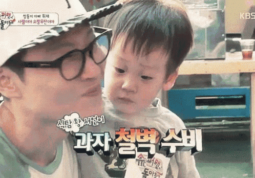 a man with glasses is kissing a little boy on the cheek