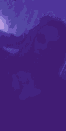 a person is laying on a bed in a dark room with a purple background