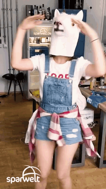 a woman wearing overalls and a cat mask dancing in front of a sparwelt.de fridge