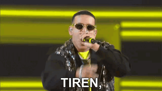 a man wearing sunglasses is singing into a microphone and the word tiren is on the bottom