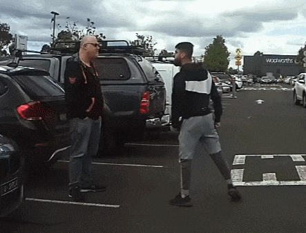 two men are standing in a parking lot in front of a woolworths