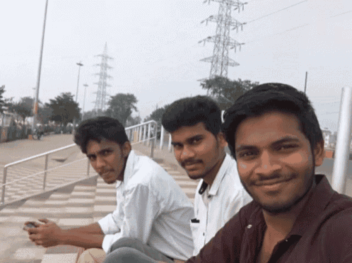 three young men pose for a picture in front of a telephone pole