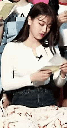 a young woman is sitting on a blanket reading a book .