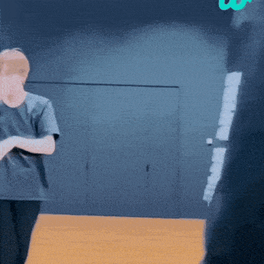 a man in a black shirt is standing in front of a wall with a green letter u on it