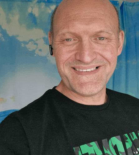 a bald man wearing a black shirt that says " lucky " smiles for the camera