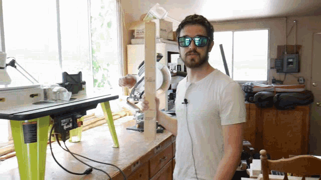 a man wearing sunglasses holds a piece of wood in front of a pelican box