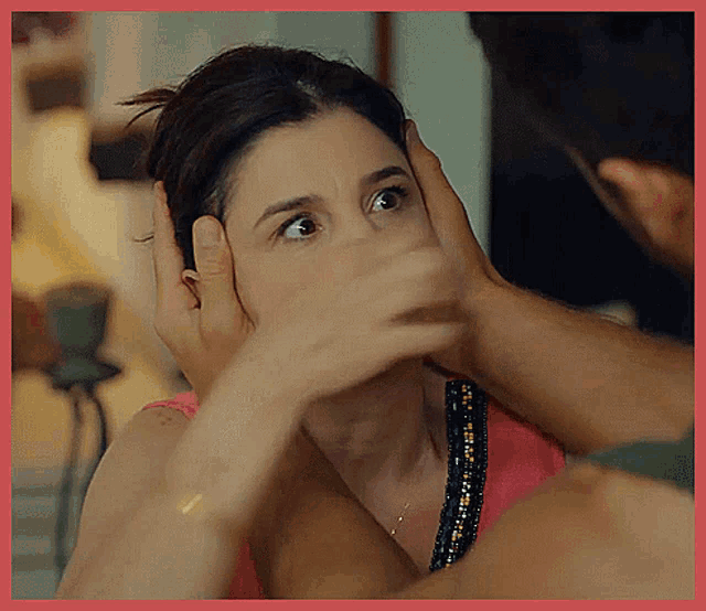 a woman covering her face with her hands while a man touches her head