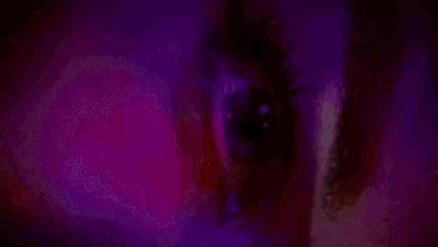 a close up of a woman 's eye with a purple glow coming out of it .