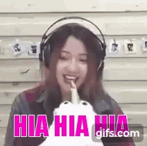a woman wearing headphones is laughing and holding a stuffed animal in her hand .