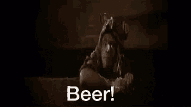 a bottle of beer is being poured into a glass in a dark room and the words beer are coming out of it .