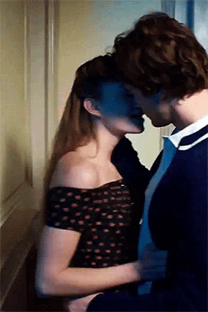 a man and a woman are kissing in a dark room