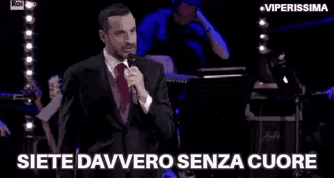 a man in a suit and tie is holding a microphone and singing into it .