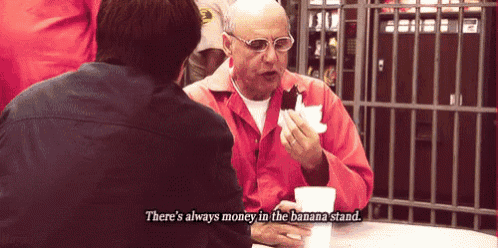 a man sitting at a table talking to another man with the words " there 's always money in the banana stand " above him