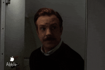 a man with a mustache is standing in a dark room with an apple logo in the corner .