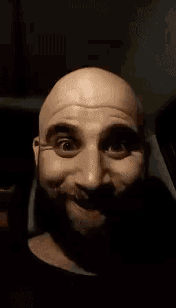 a bald man with a beard is making a funny face with hebrew writing behind him