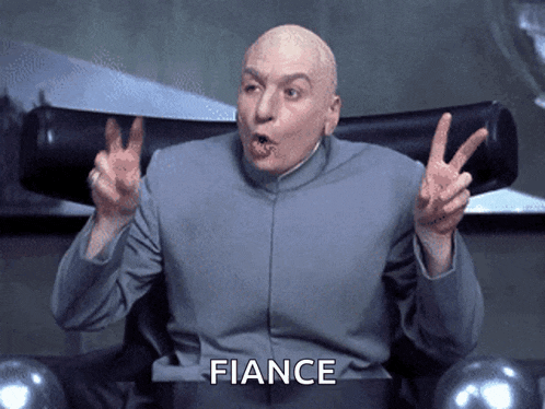 a bald man sitting in a chair giving a peace sign with the word fiance below him