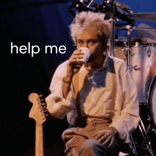 a man is drinking a cup of coffee while sitting next to a guitar on a stage .