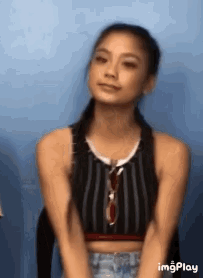 a woman in a striped tank top is sitting in front of a blue wall .