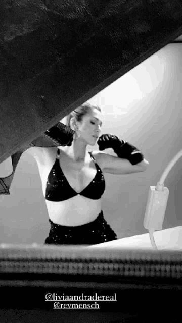 a black and white photo of a woman in a black bra and skirt