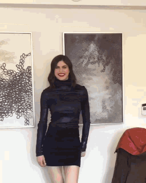 a woman in a black dress is standing in front of two framed pictures