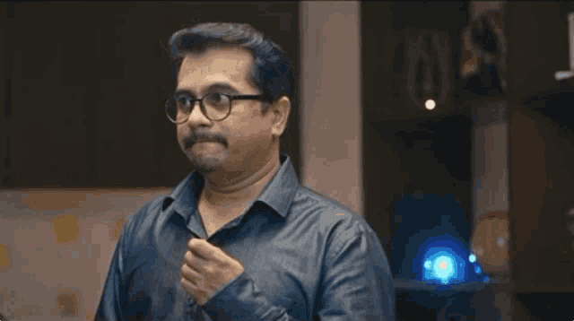 a man with glasses and a mustache is standing in a room .