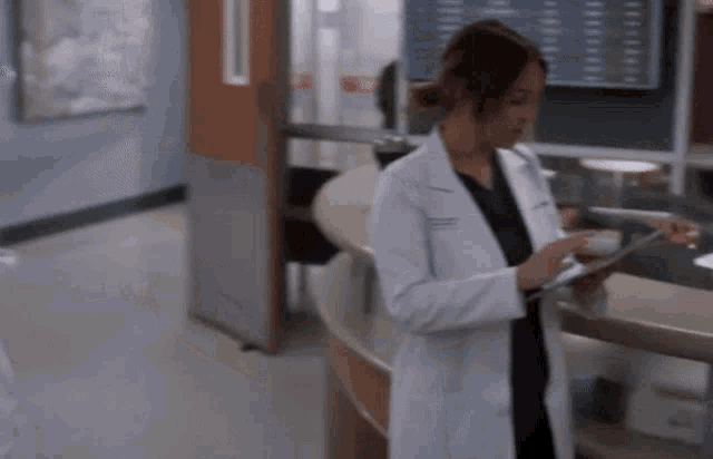 a woman in a lab coat is using a tablet computer in a hospital .