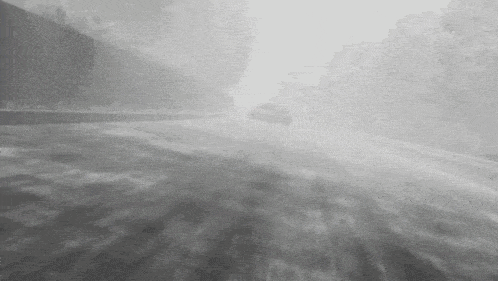 a car is driving down a foggy road .