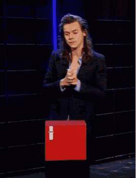 a man in a suit is standing in front of a red box with the letter i on it ..