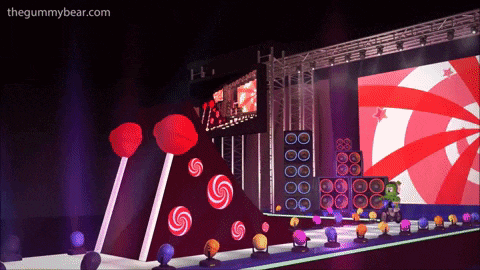 a stage with lollipops and speakers and the website thegummybear.com at the top