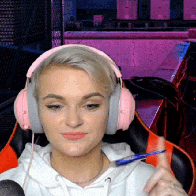 a woman wearing pink headphones holds a pen in her hand