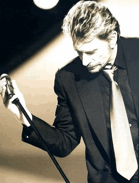 a man in a suit and tie holds a microphone