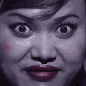a close up of a woman 's face with big eyes and red lips making a funny face .