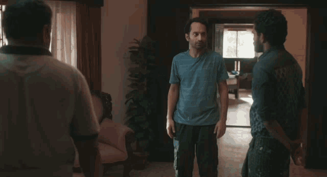 a man in a blue shirt talks to two other men