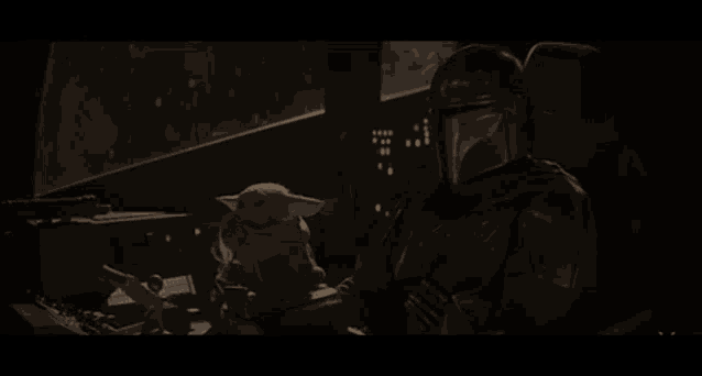 a man in a helmet sits in a dark room holding a baby