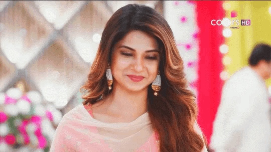 a close up of a woman wearing a pink dress and earrings smiling .