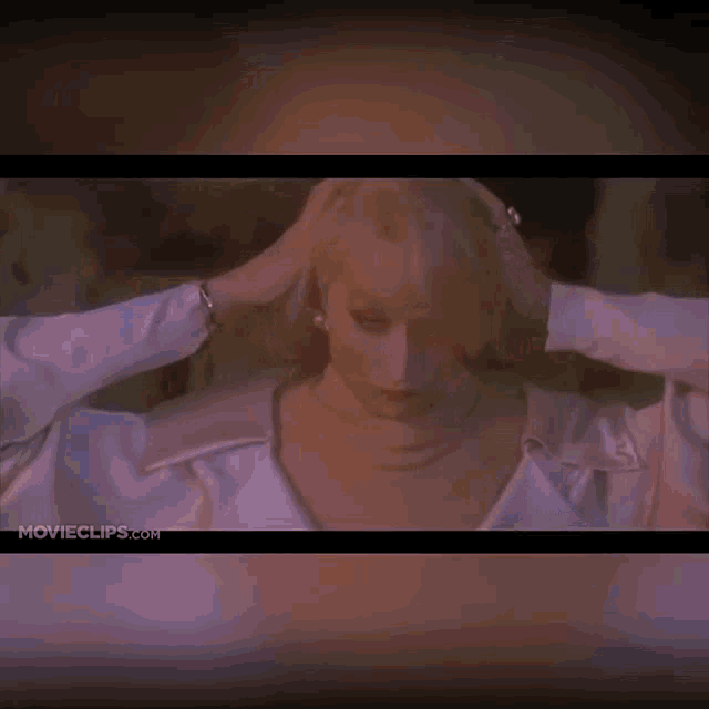 a woman in a white shirt holds her hands to her head in front of a movie clip from movieclips.com