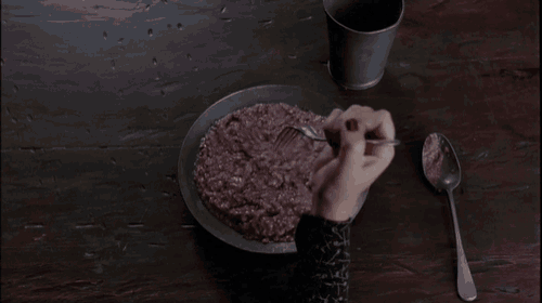 a person is eating a bowl of food with a fork