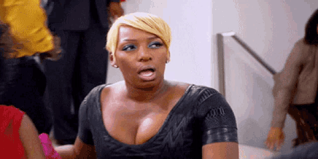 a woman in a black dress is making a funny face while standing in a crowd .