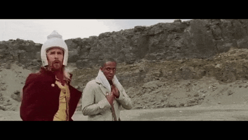 a man with a beard is standing next to another man in a field .