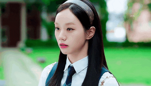 a young girl wearing a headband and a tie is looking at the camera .