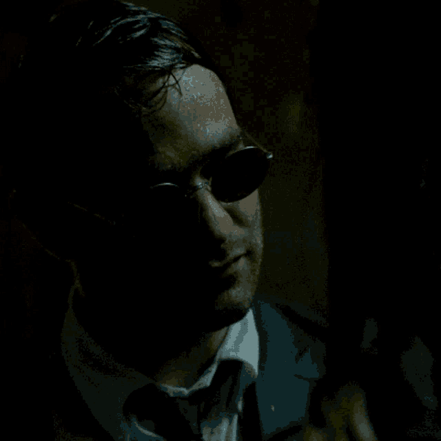 a man in a suit touches a woman 's face in the dark