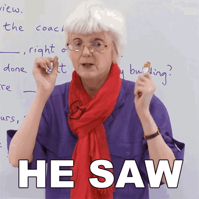 a woman with glasses and a red scarf says he saw in front of a white board