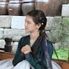 a woman in a traditional korean dress is sitting in front of a brick wall holding an umbrella .