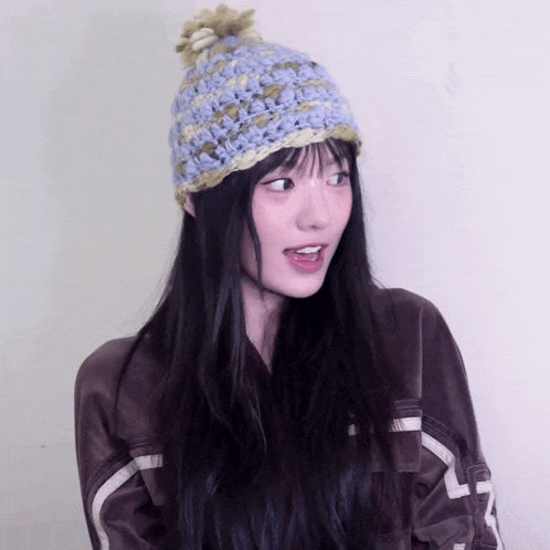 a woman wearing a crocheted hat and a jacket with the letter l on the sleeves
