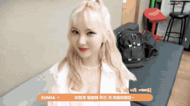 a woman with blonde hair is sitting on a couch with a sign that says eunha